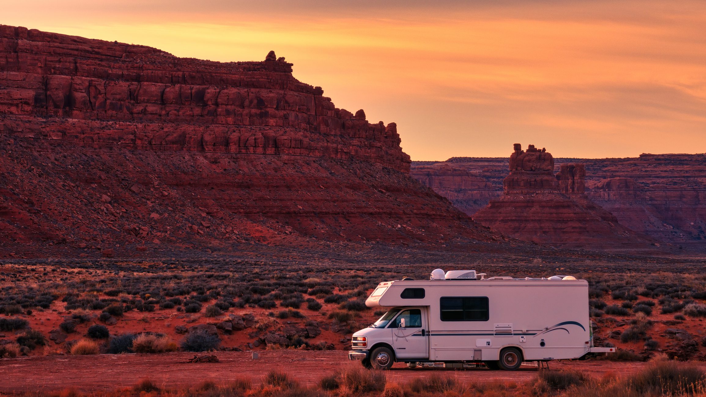 Motorhome under colorful desert sky.