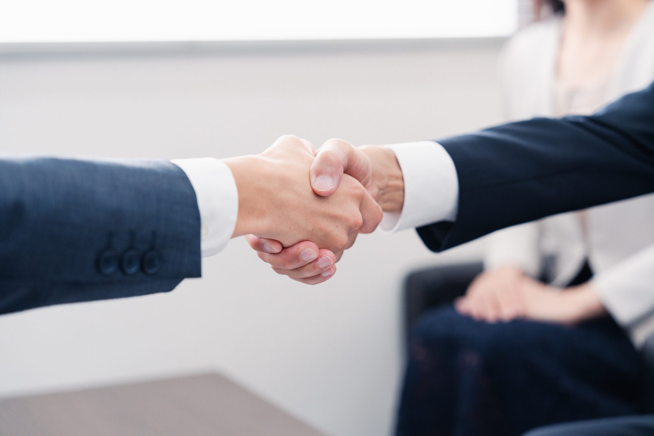 Two people shaking hands in office